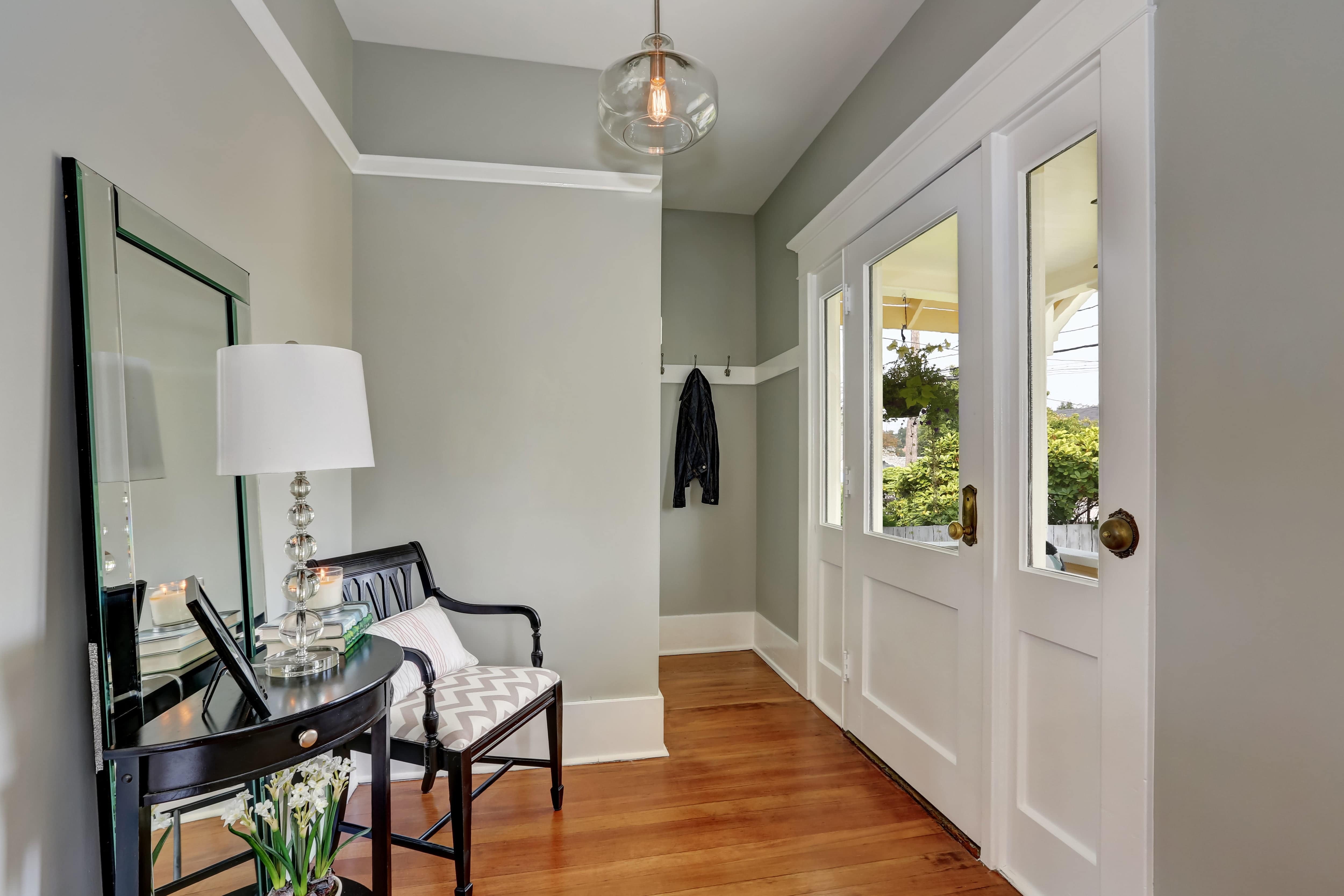 An entryway with seating, an oversized mirror, and a side table with decor