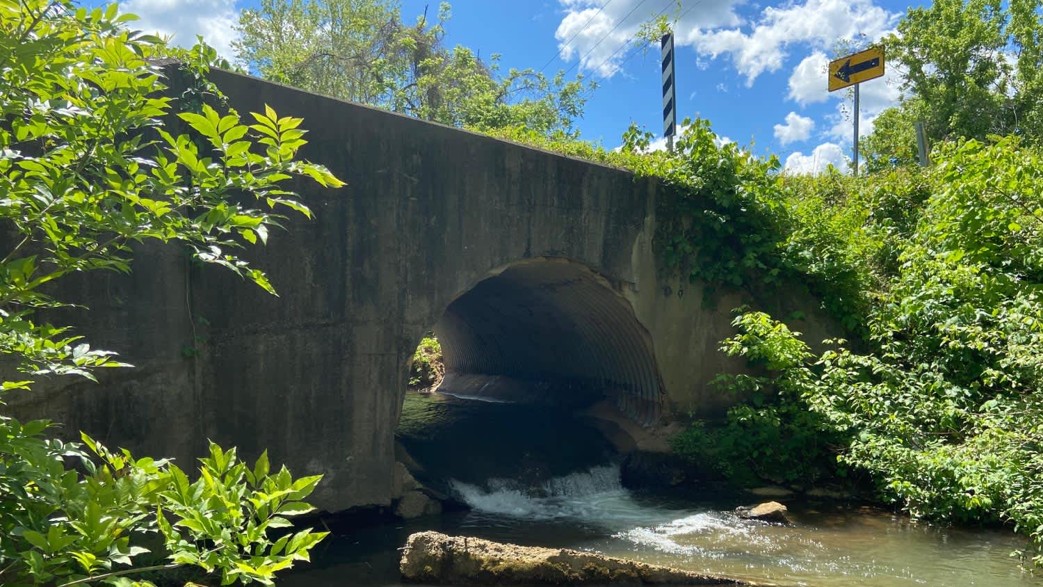 A culvert with stream passing under a road