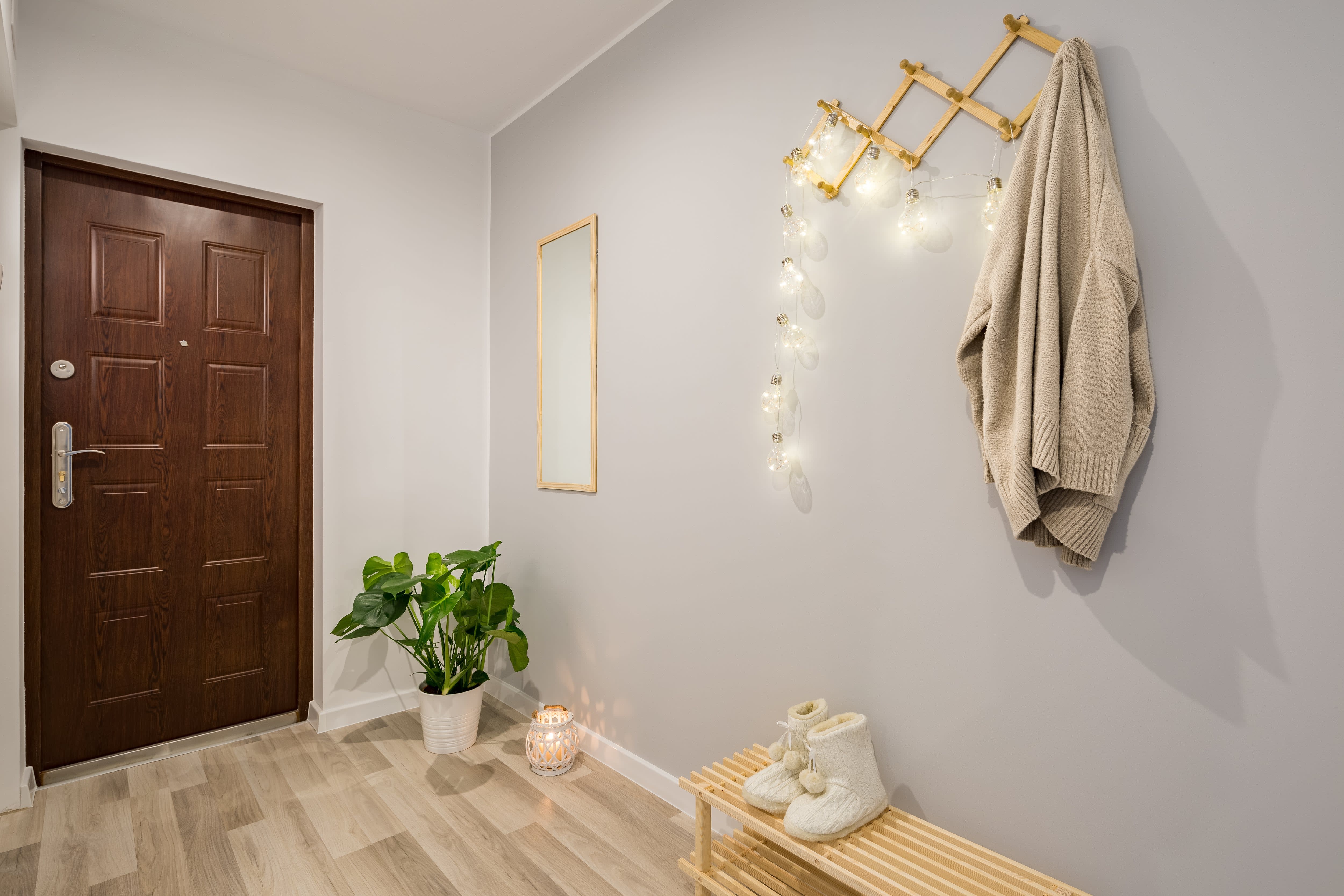 A bright and minimalistic entryway with a mirror, wall rack, and small bench