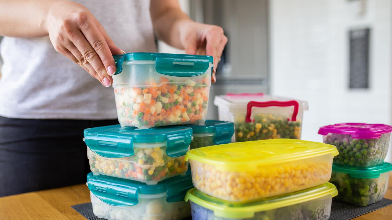 Woman preparing containers with frozen mixed vegetables