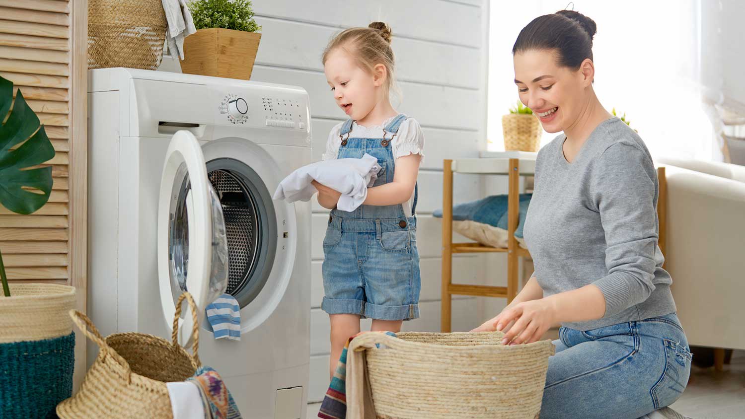 Little daughter helping mom with laundry