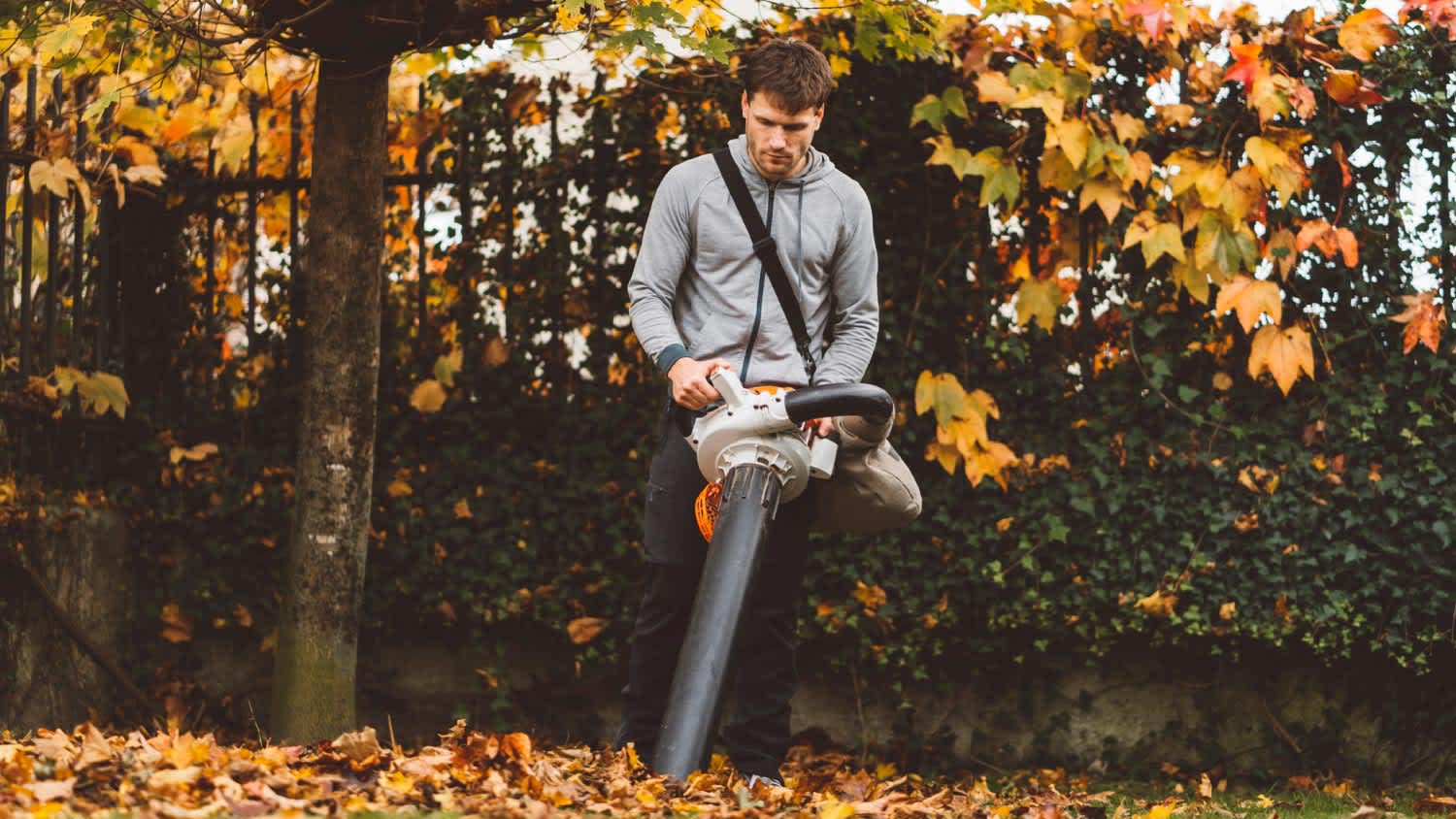 A man using leaf vacuum to clean the garden