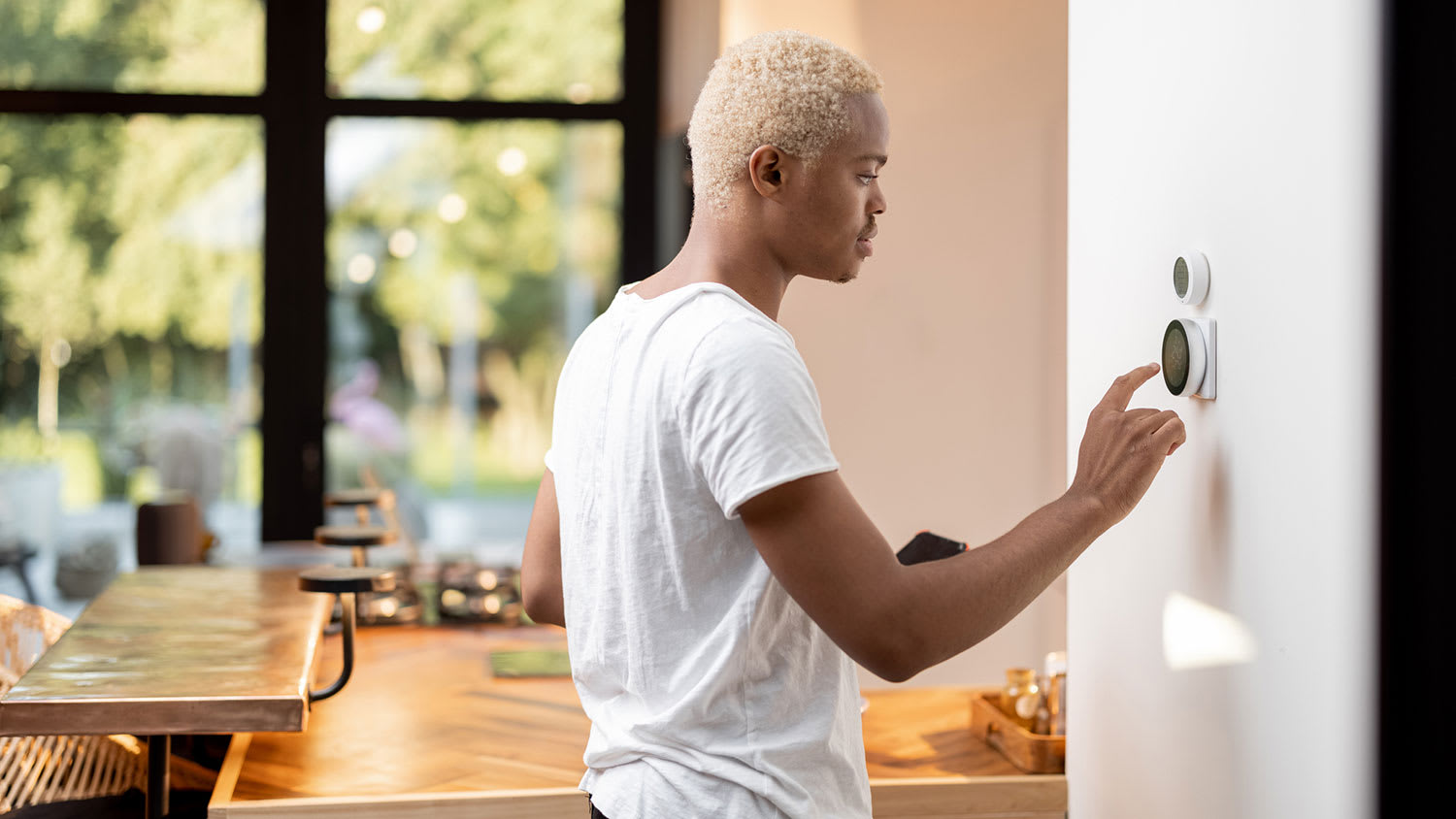Young man setting up a smart thermostat at home