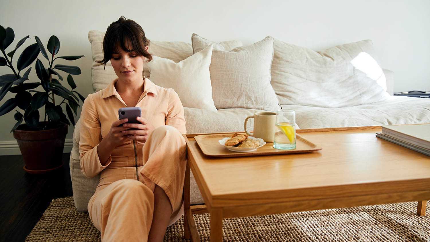 woman looking at phone while sitting on floor