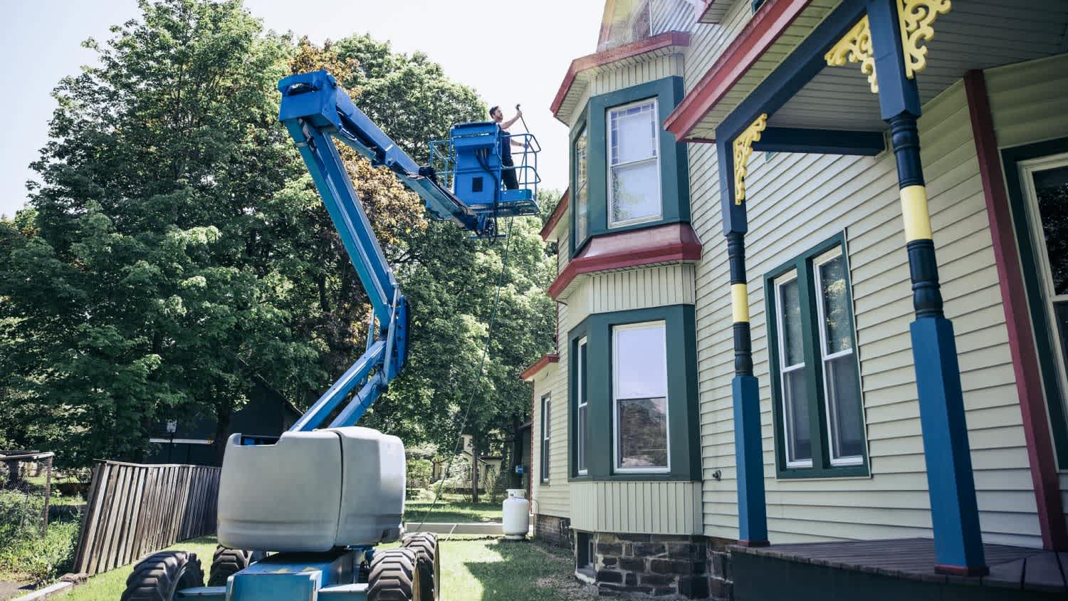 A man on cherry picker performing home maintenance