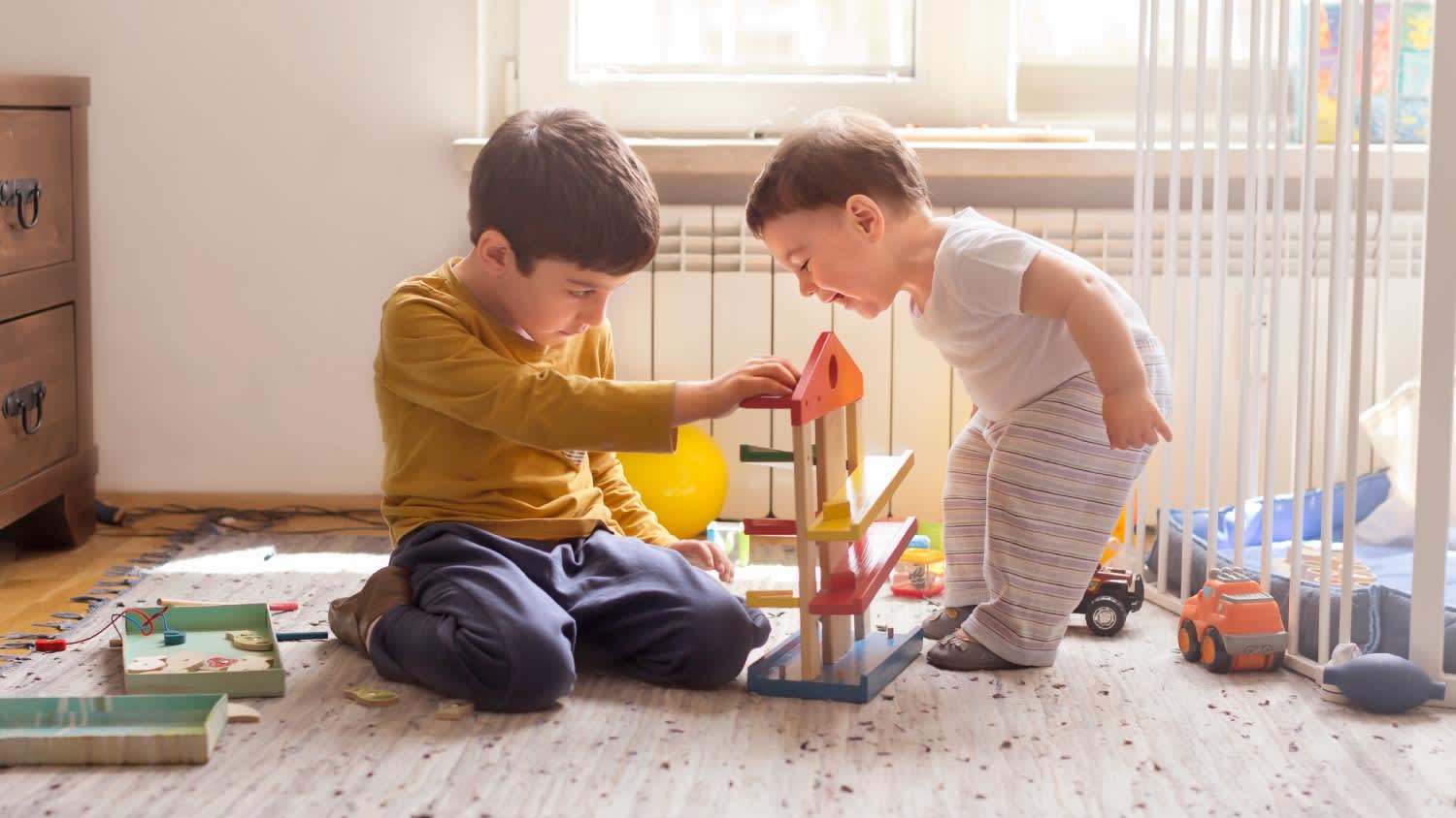 Sibling playing together with wooden toy
