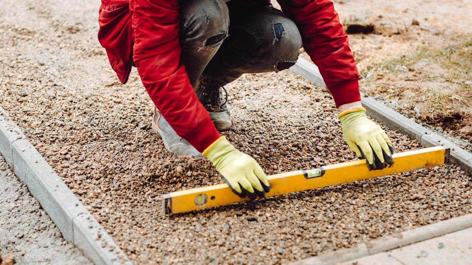 A worker leveling decomposed granite on a patio
