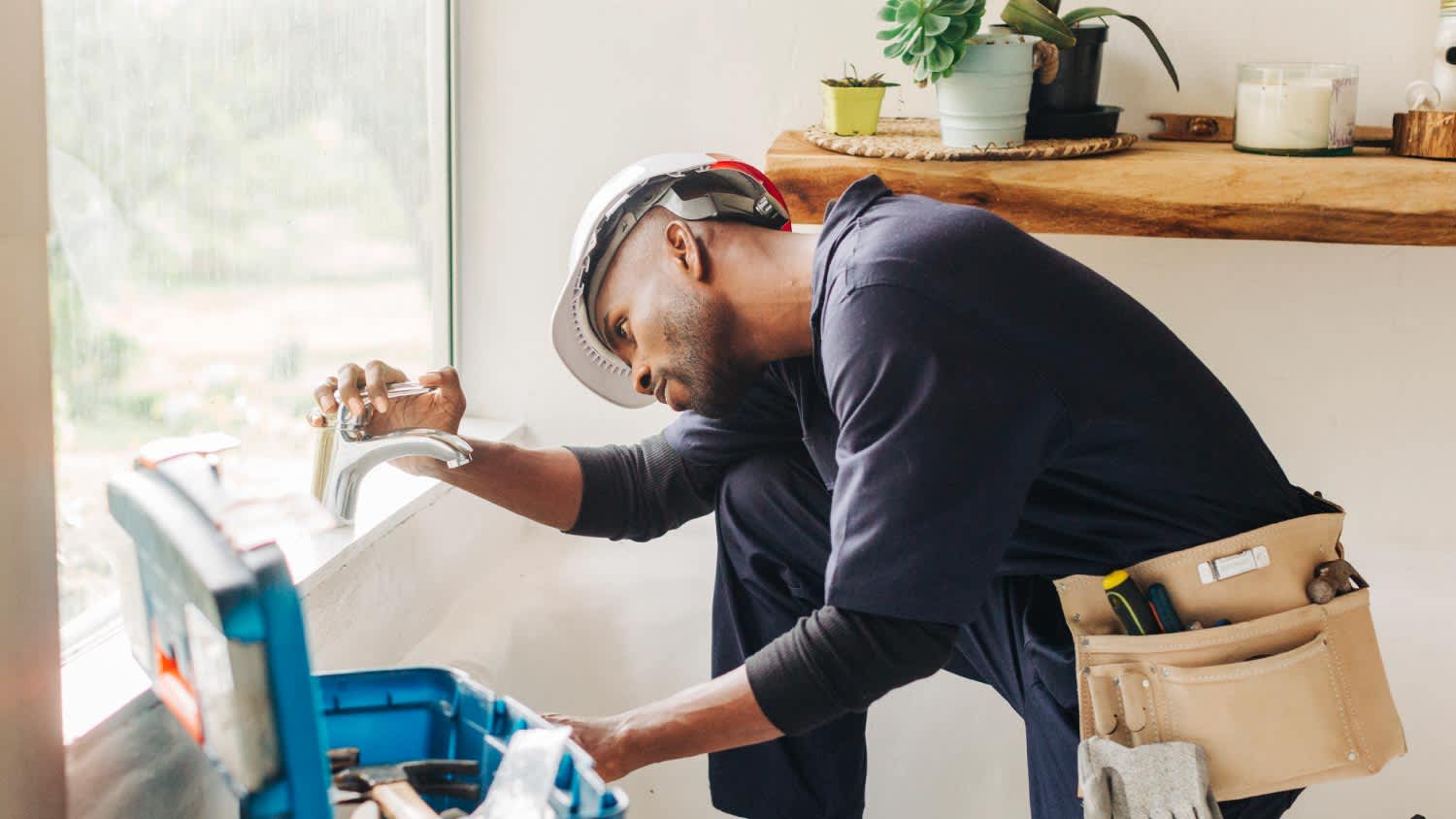 A plumber fixing a leaking bathroom faucet