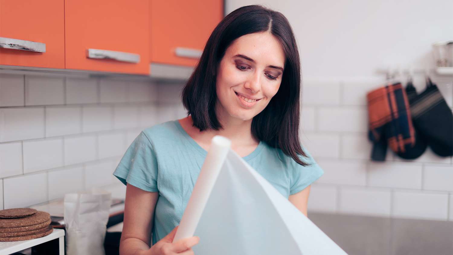 woman pulling on a roll of wax paper while in the kitchen