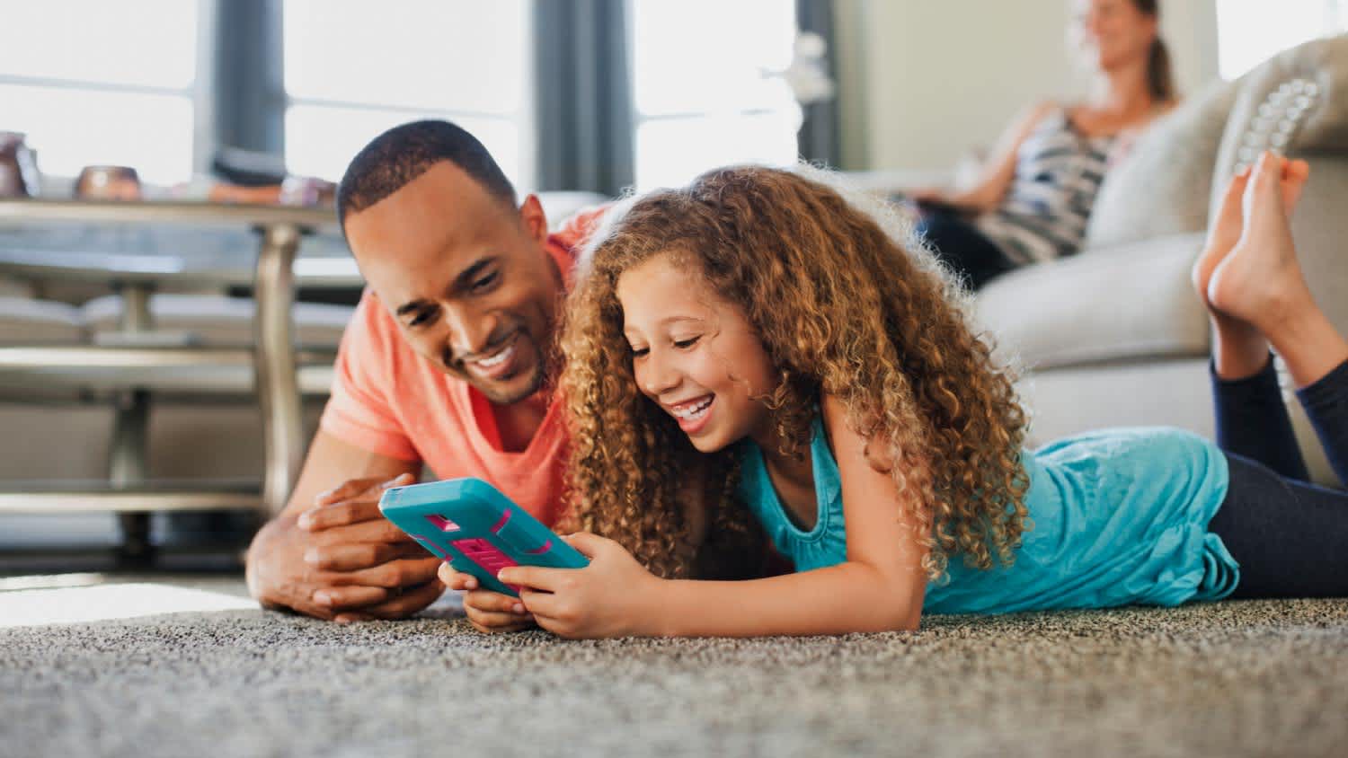 Father and daughter playing while lying on floor at home
