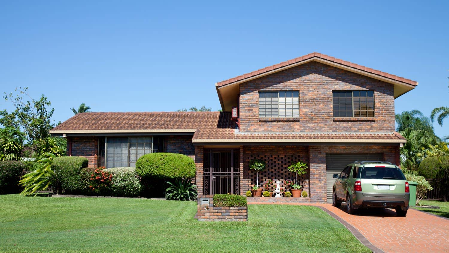 A brown brick house with a landscaped garden