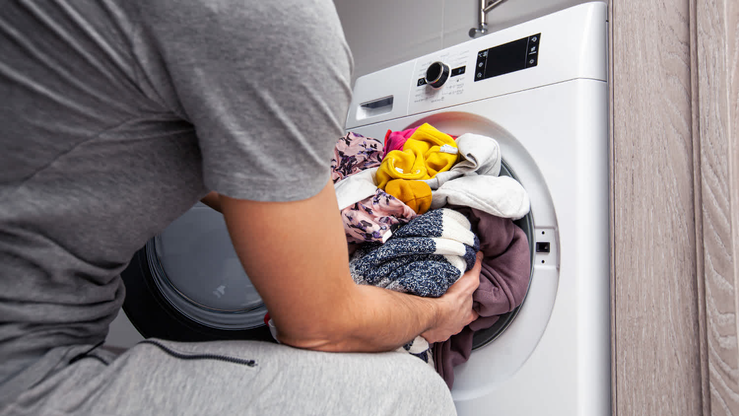 man stuffing too many clothes into the washing machine