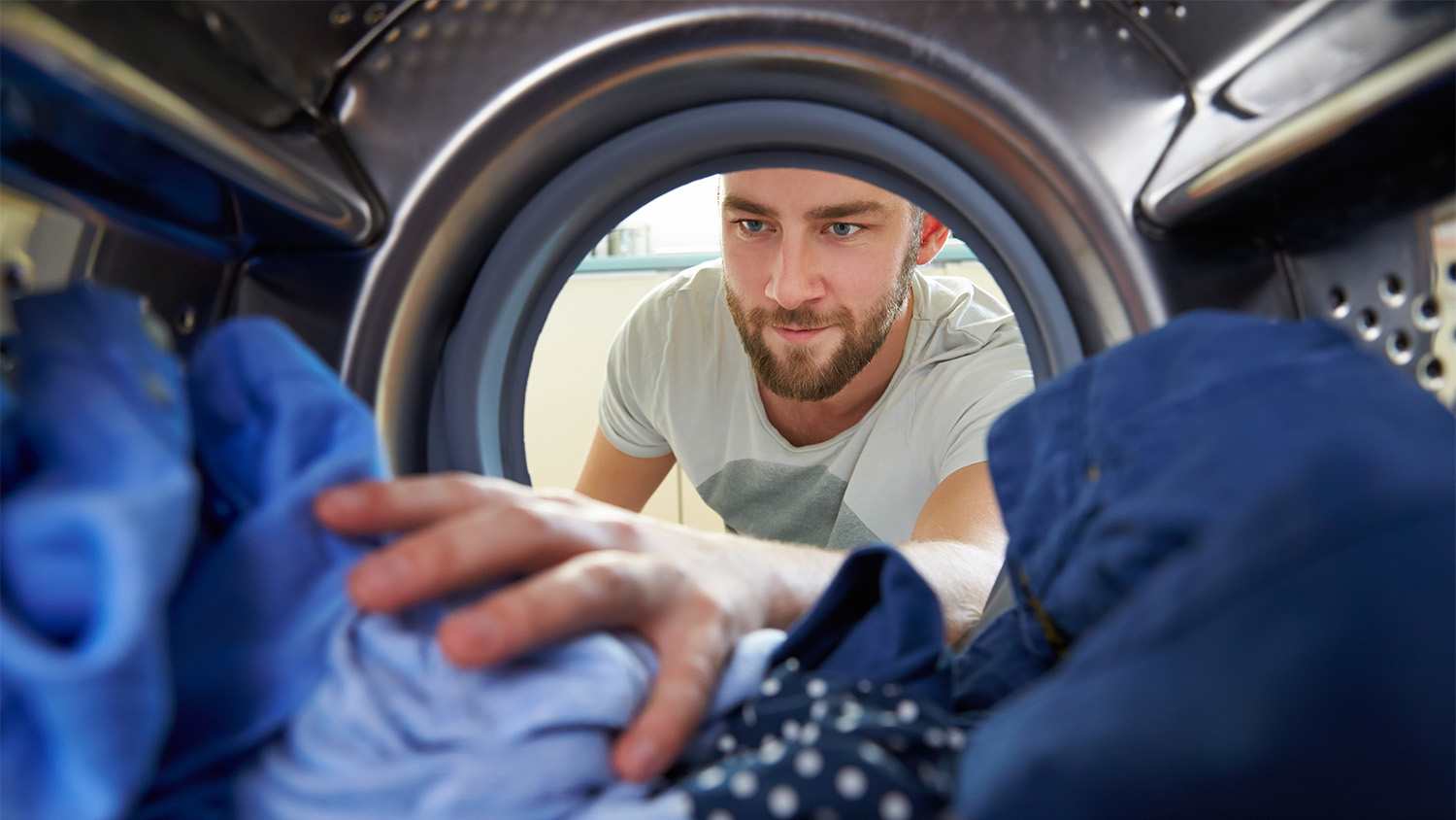 man reaching inside the washing machine.