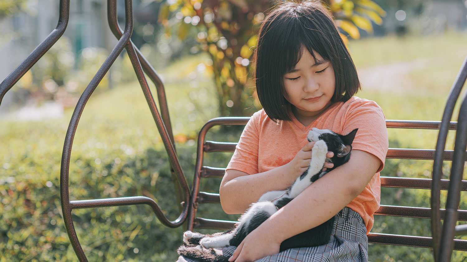 Girl cuddling with her cat in the backyard