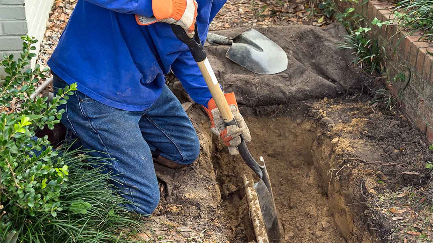 Man digging trench to sewer line