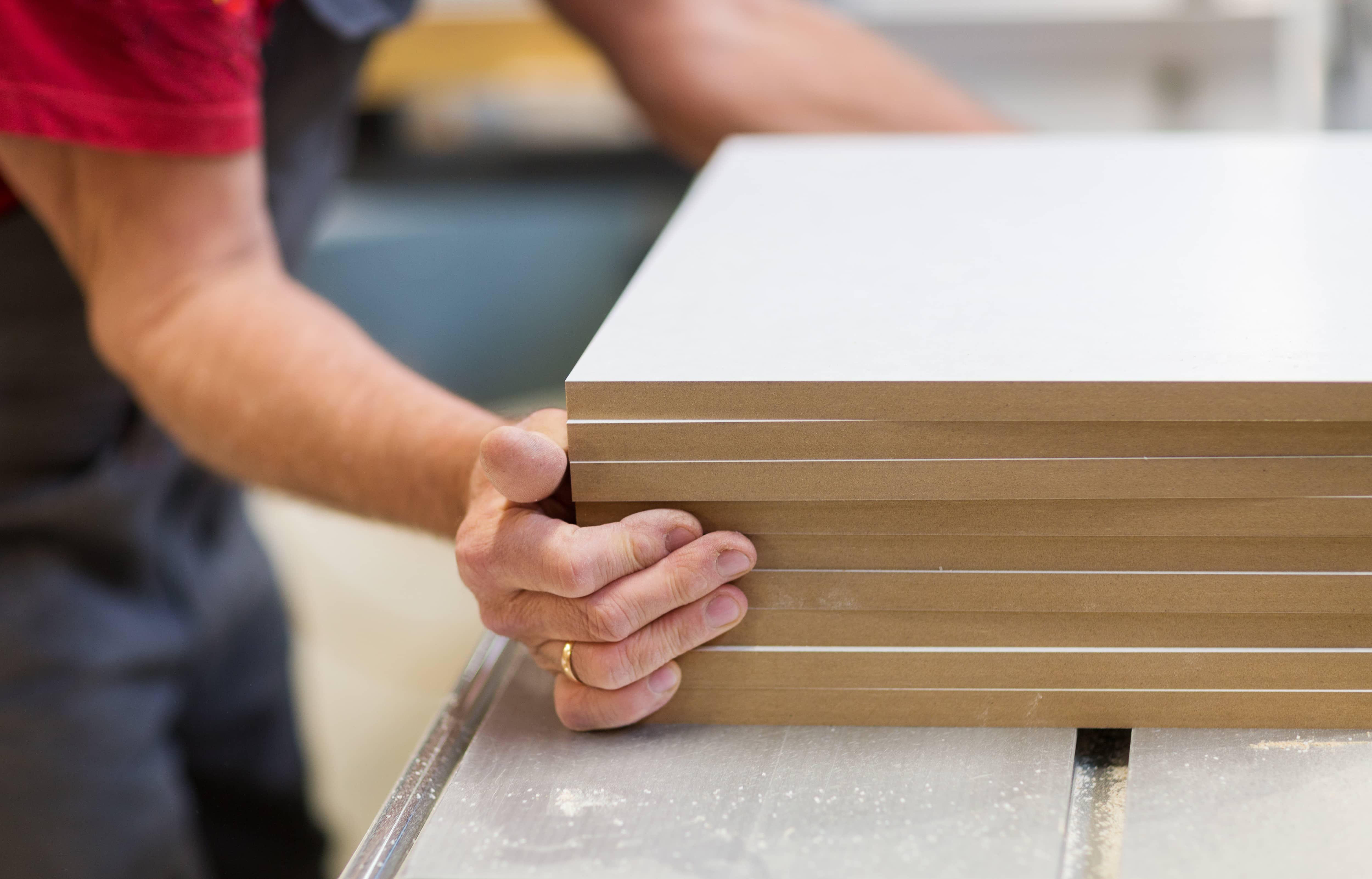 Carpenter with stacked pile of MDF wood boards