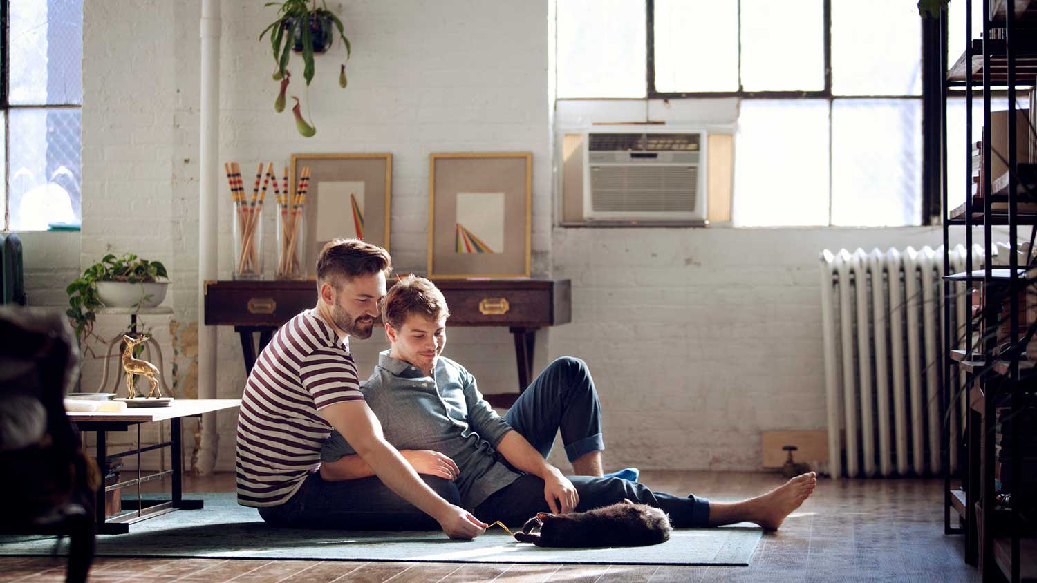 Couple sitting on the floor playing with their cat
