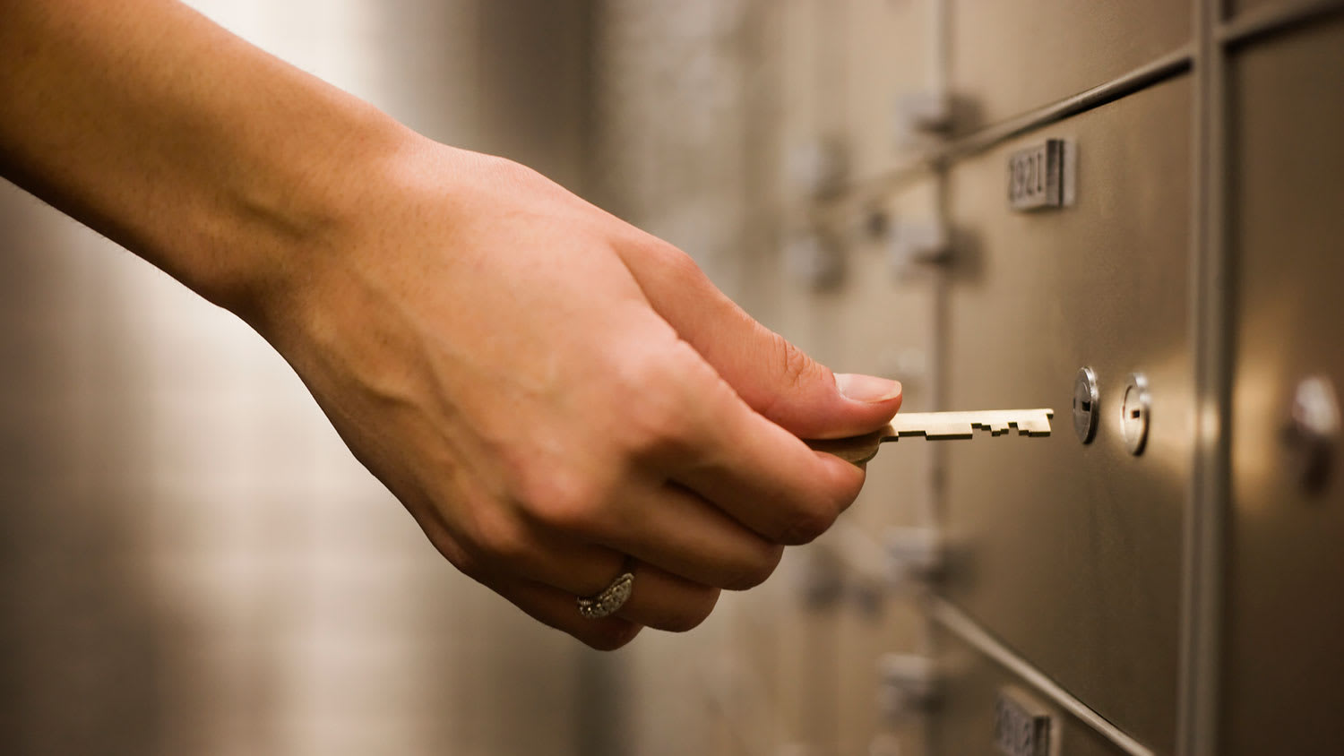 Woman using key to open a safety deposit box