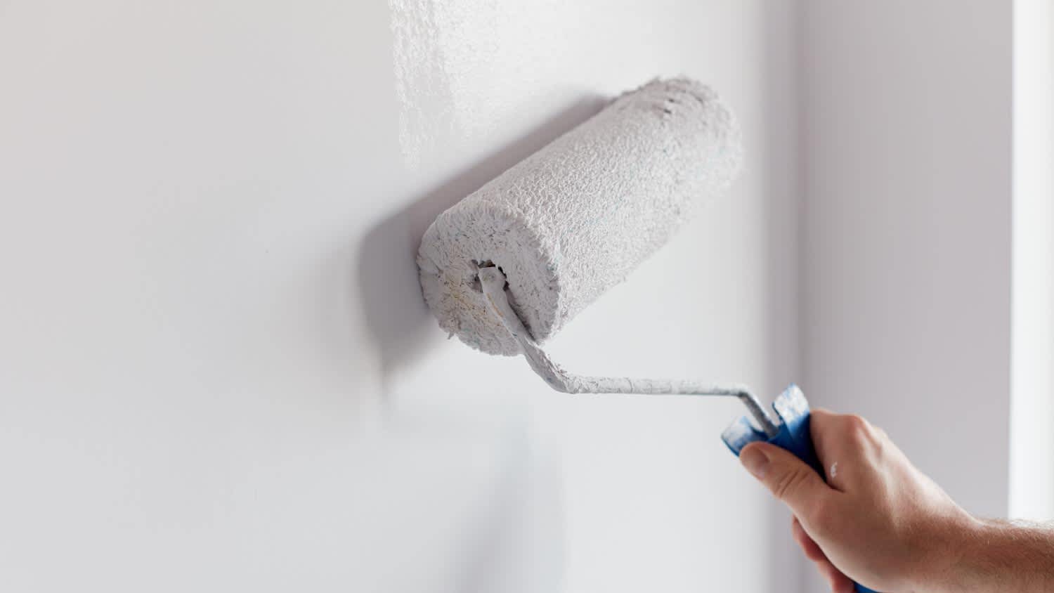 A man painting wall with paint roller