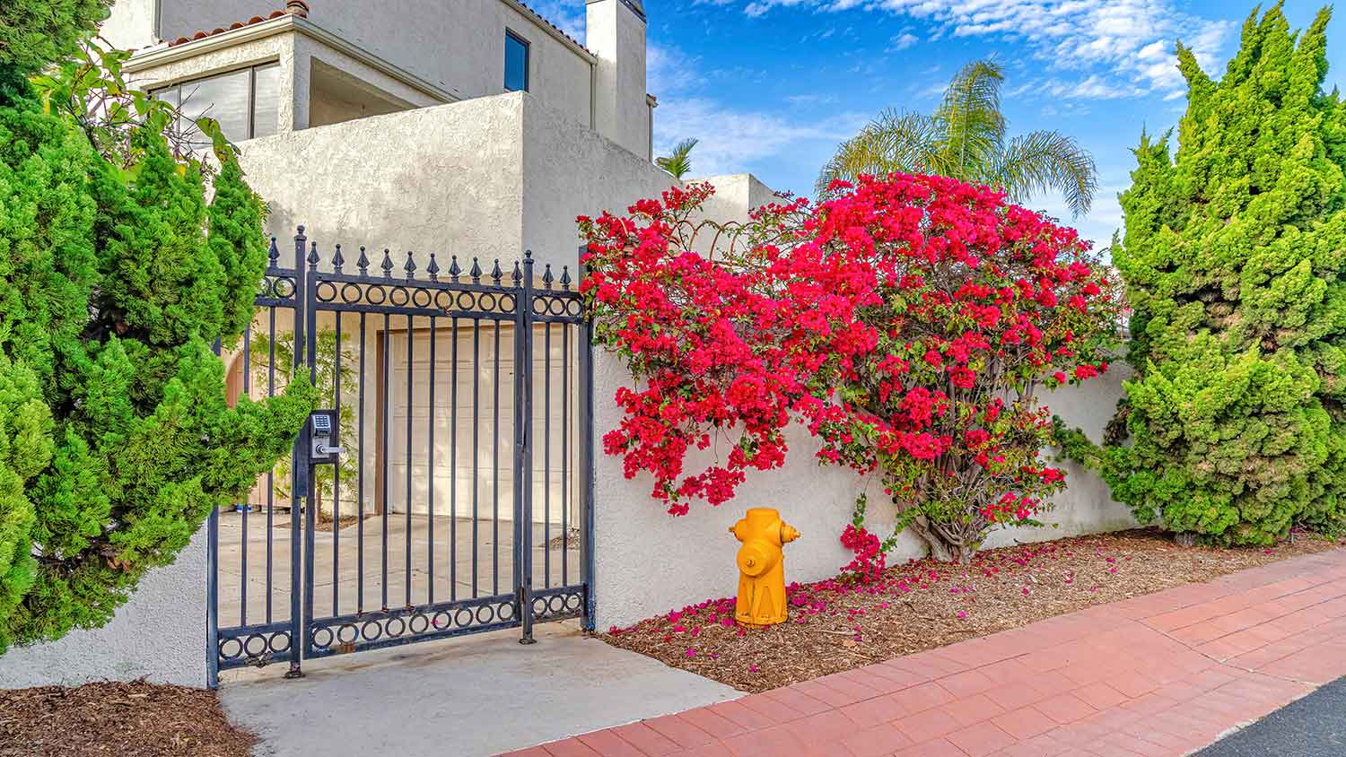 Yellow fire hydrant next to a house with a gate