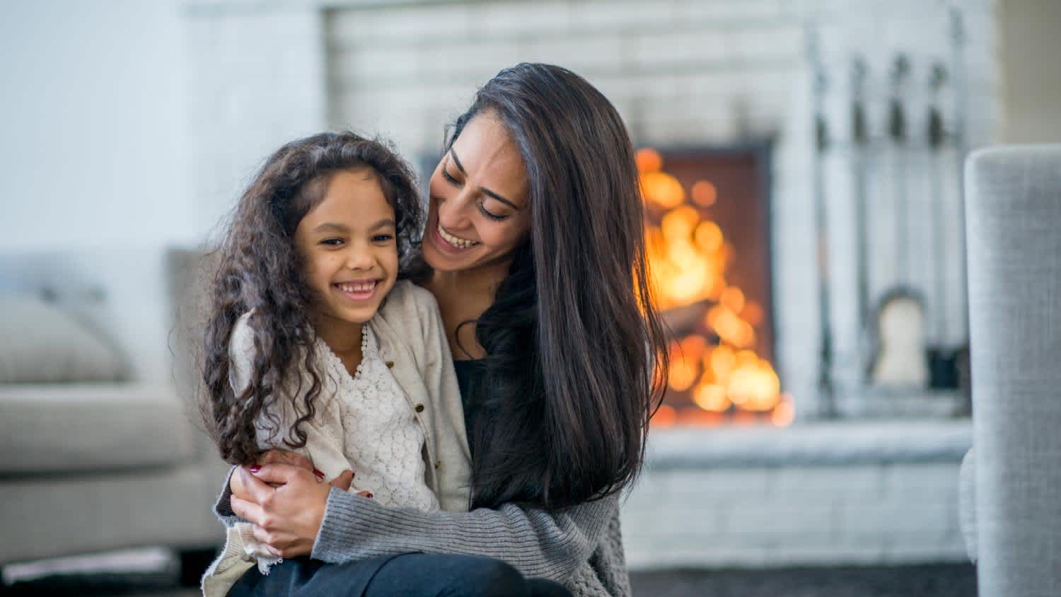 Mom and daughter sitting on the carpet in front of the fire