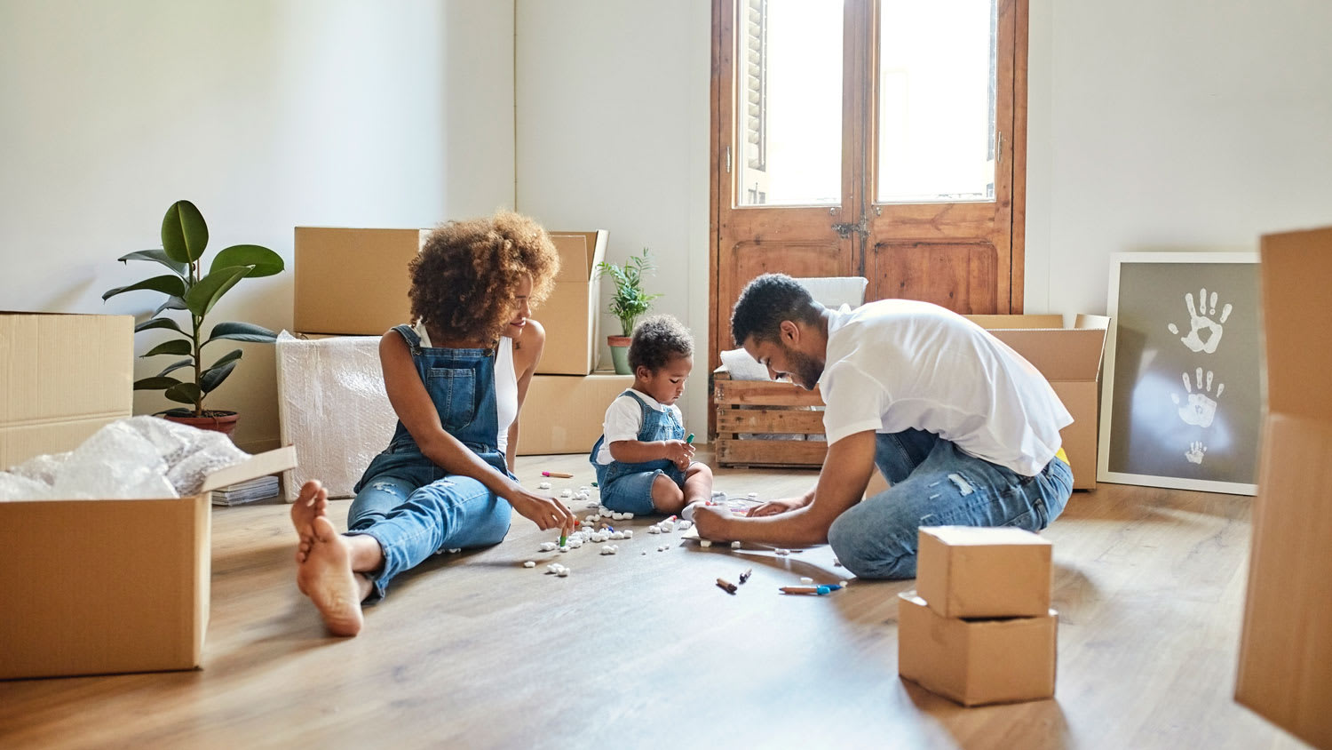 A couple with their baby opening moving boxes on the floor