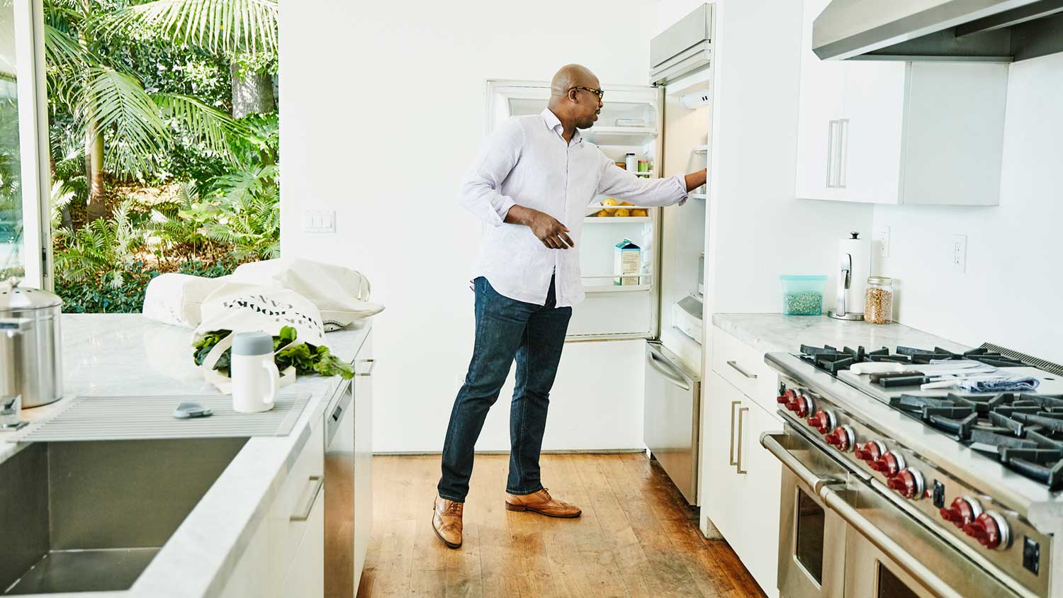 Man in the kitchen putting groceries in the refrigerator