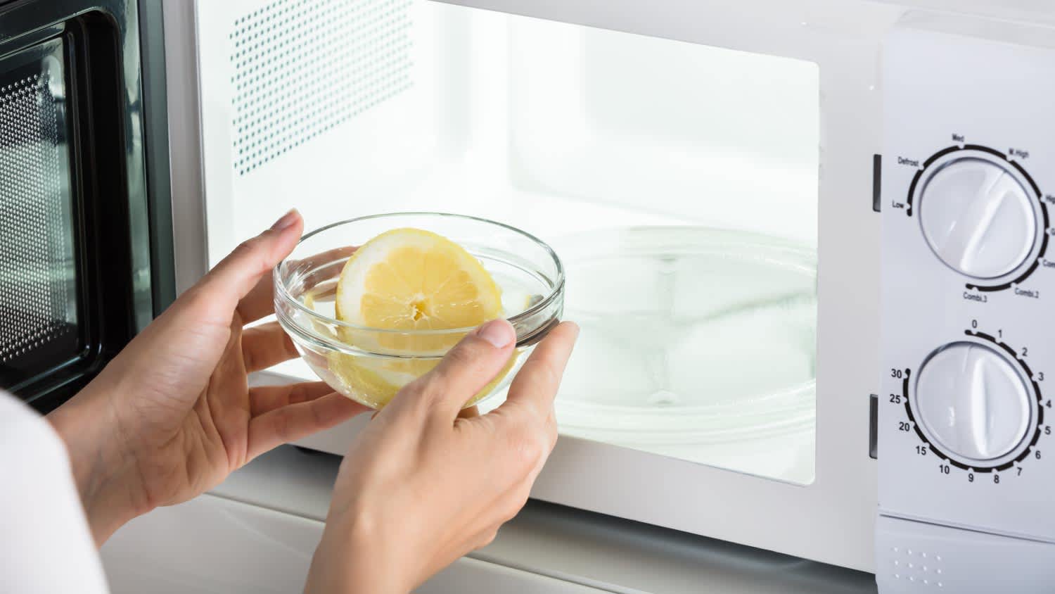 A woman putting bowl of slice lemon in microwave