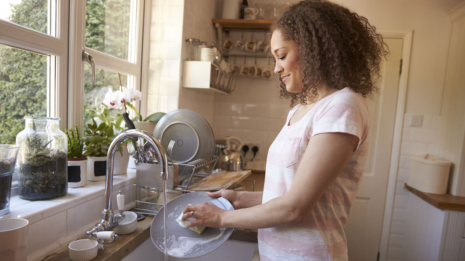 Woman washing dishes at farmhouse sink