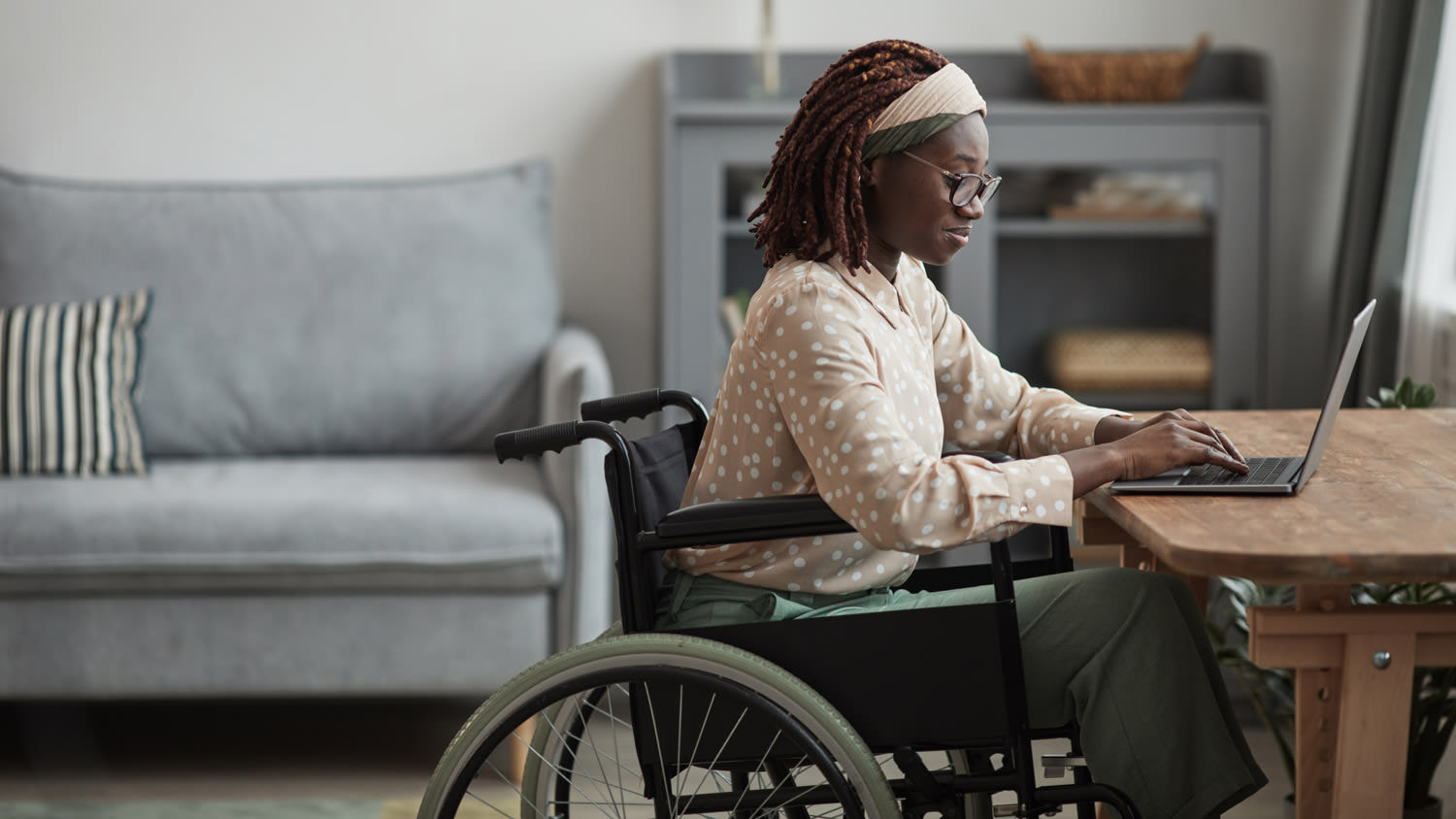 A young woman in a wheelchair working from her living room