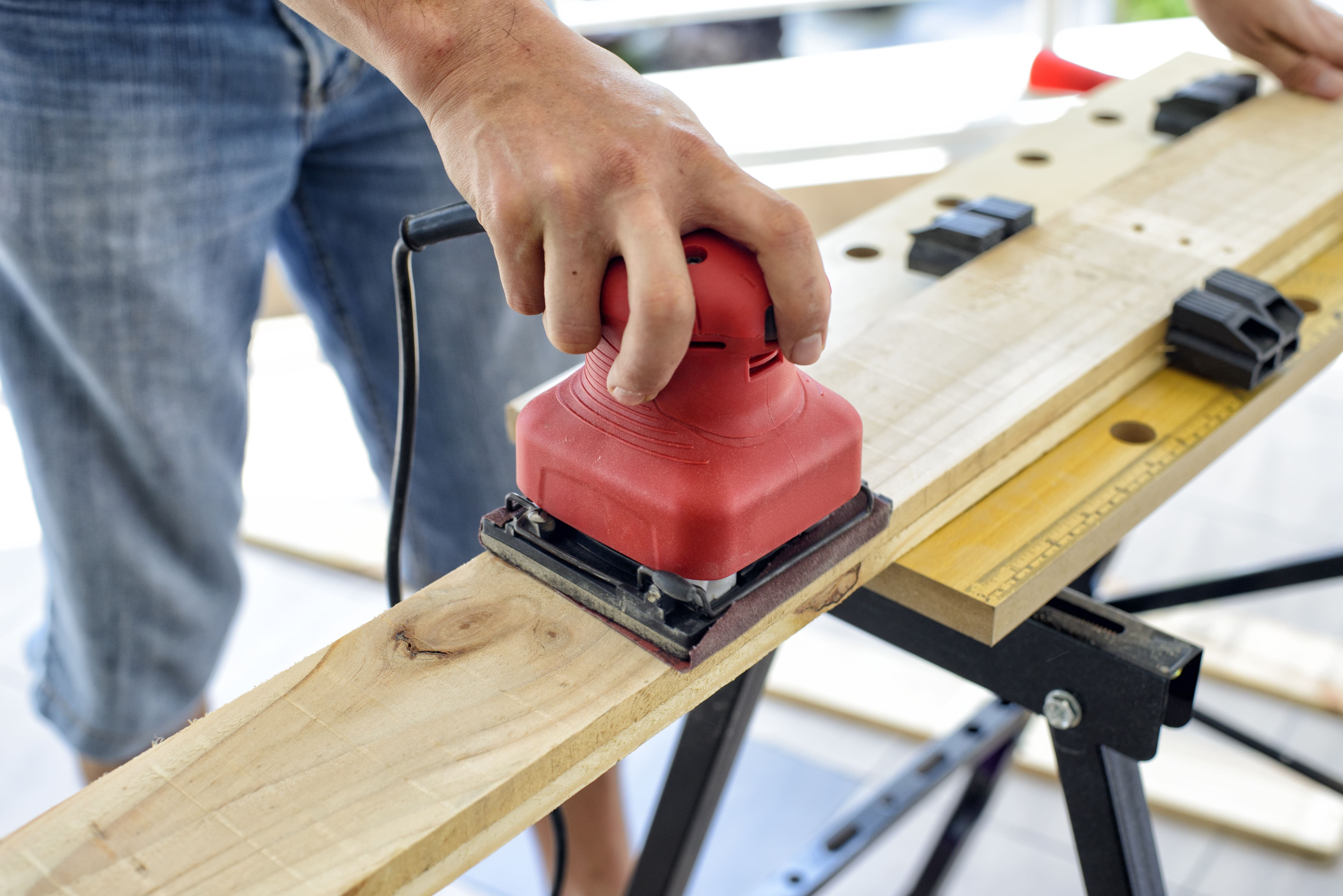 Sanding piece of wood with a palm sander