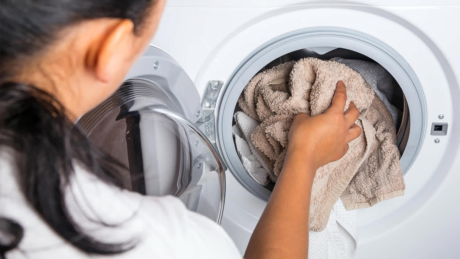 woman putting towels in the washing machine
