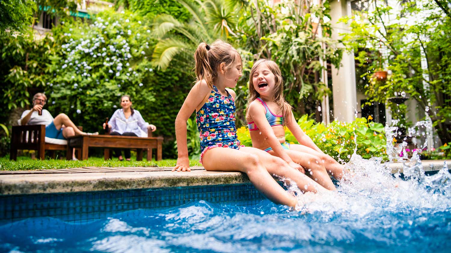Little girls sitting at poolside splashing water