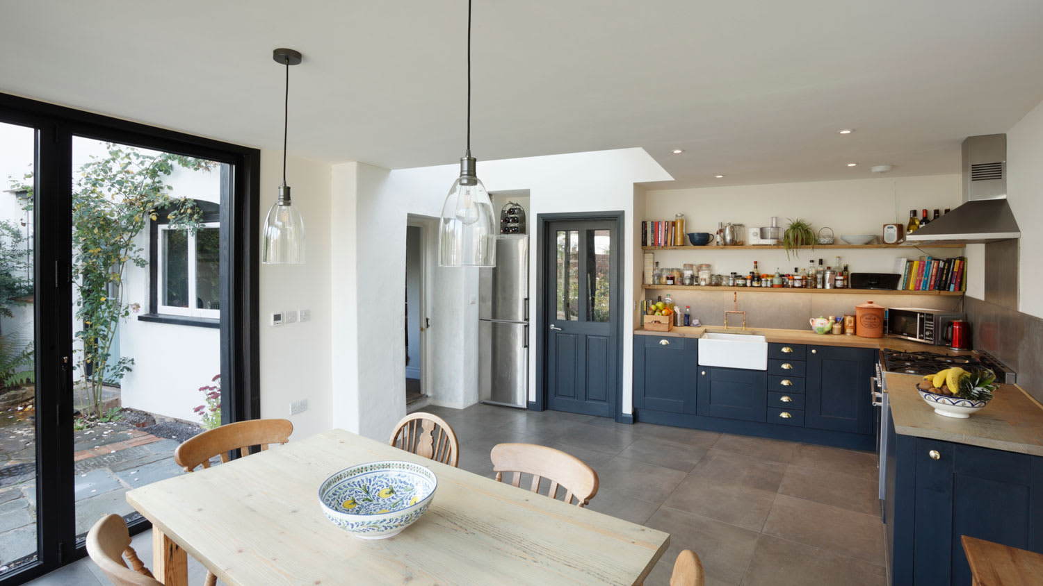 A spacious transitional kitchen with blue cabinets and wooden countertops