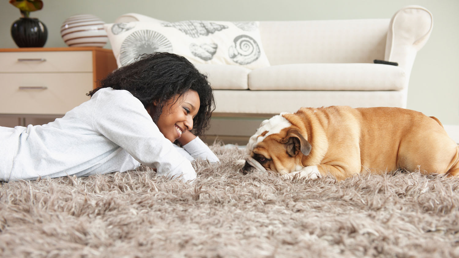 A woman lying on the carpet with her dog