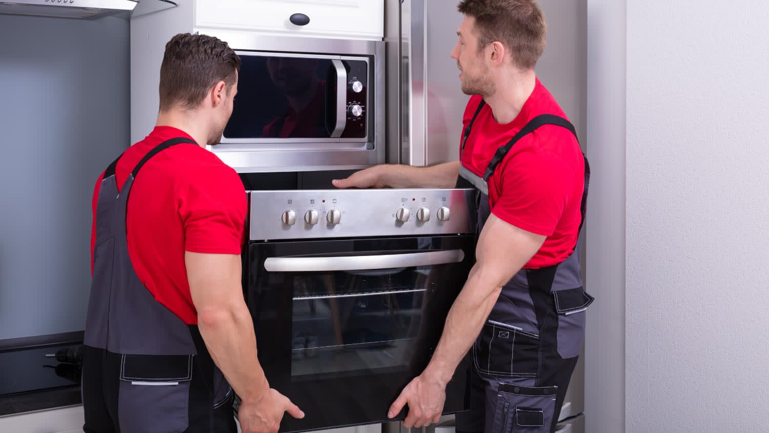 Workers placing modern oven in kitchen