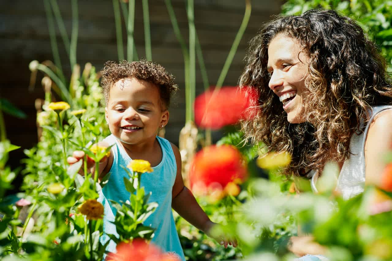 A woman and child smiling and laughing in garden with flowers