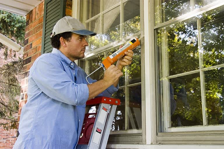 A man contractor caulks a new window frame