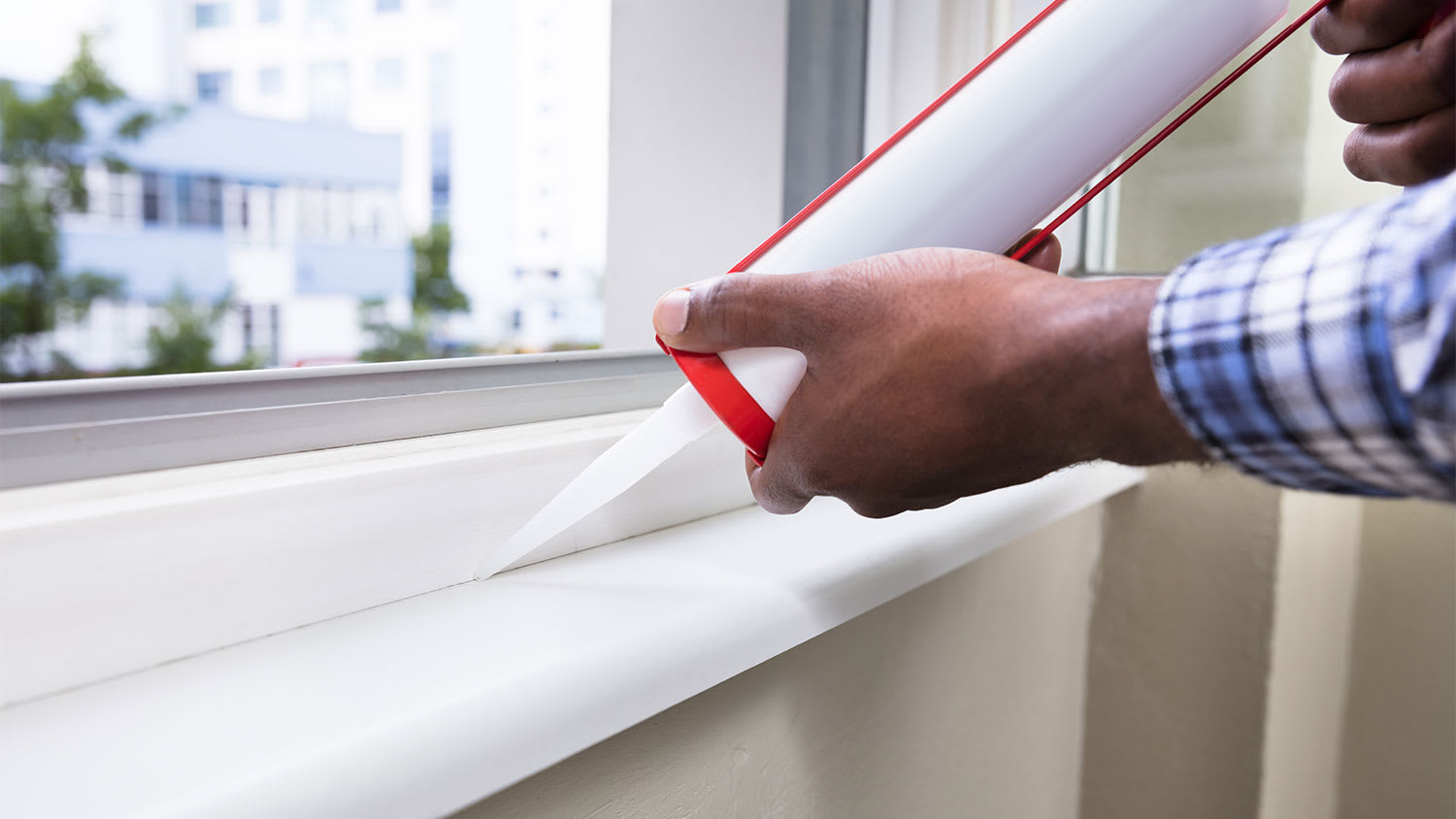 A man contractor caulks a new window frame