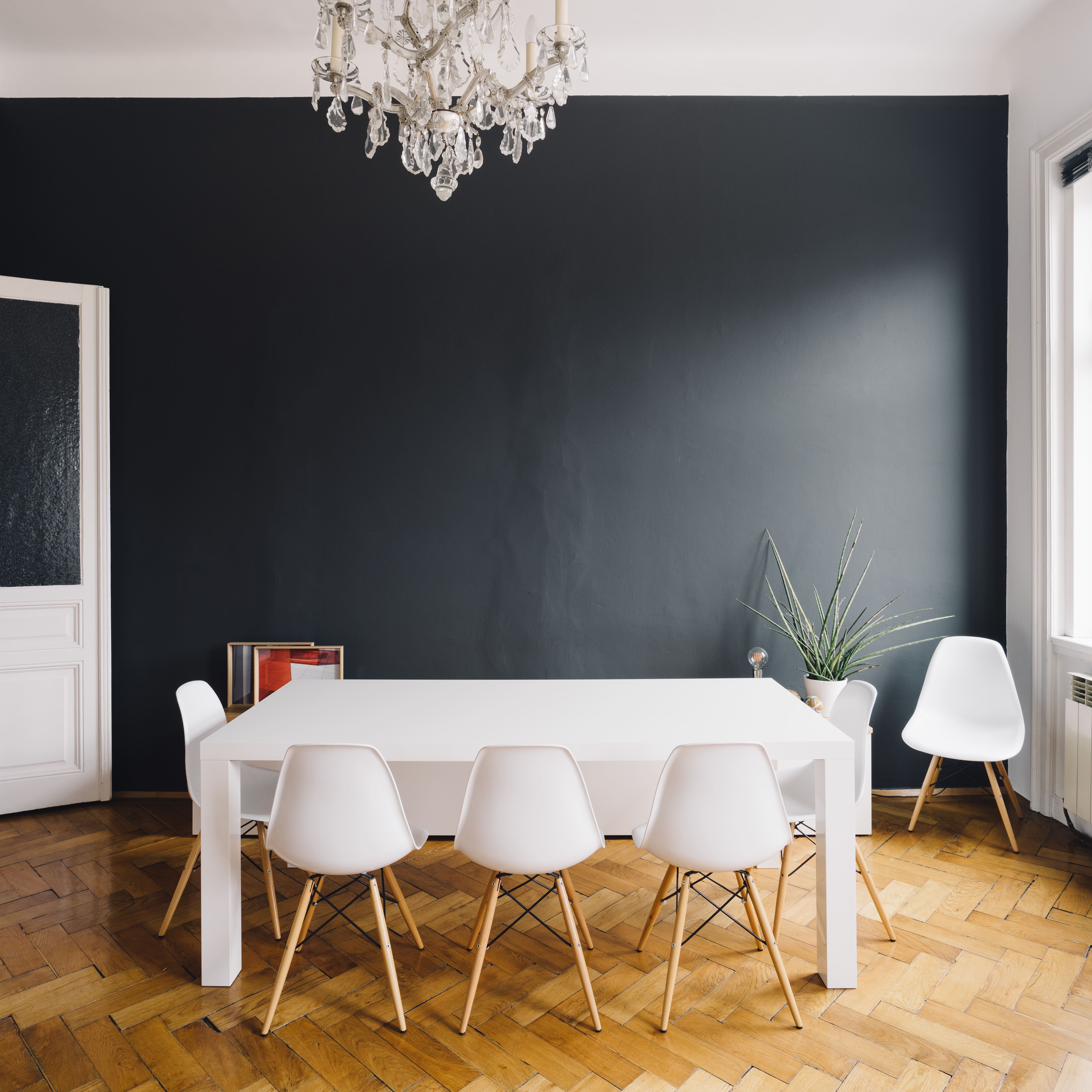 Black accent wall in dining room with white tables and chairs