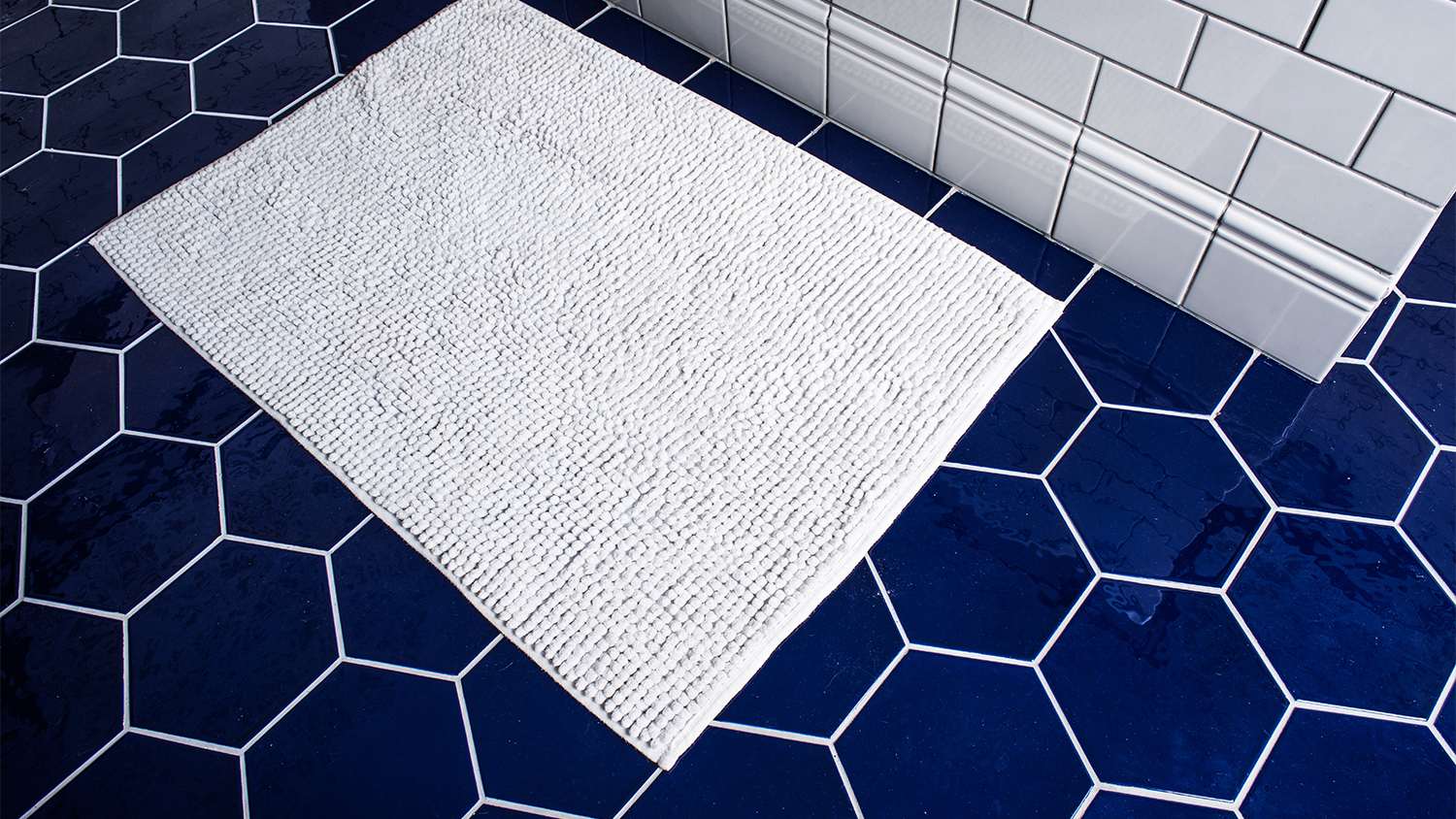 white cotton bathroom rug on blue tile floor