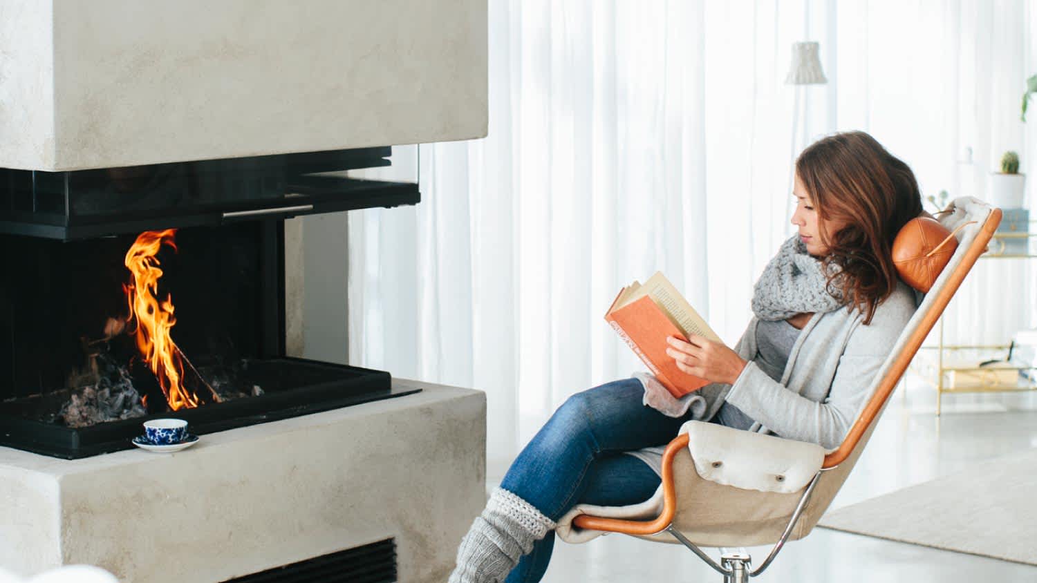 A woman reading book in front of fireplace