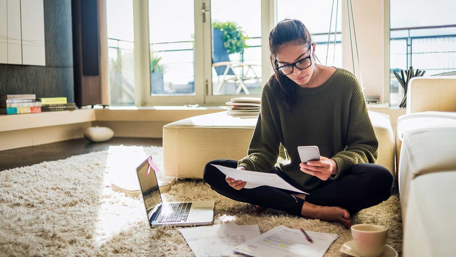 Woman sitting on the floor using laptop and phone