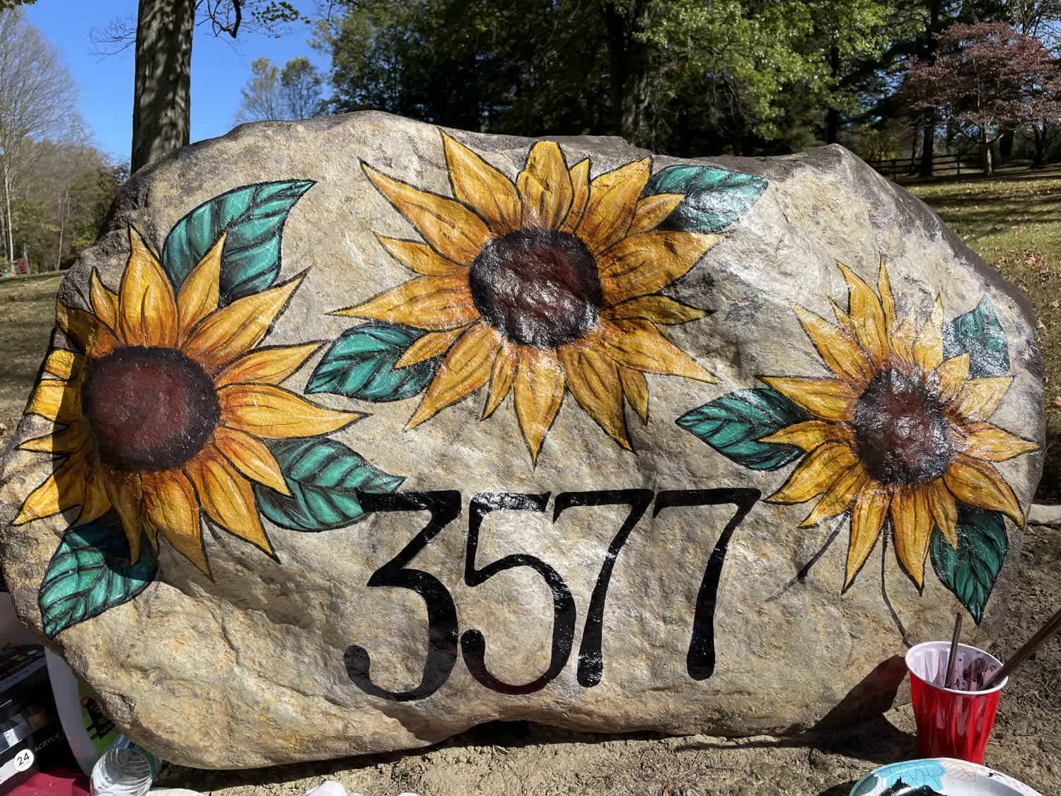 A hand-painted sunflower address rock