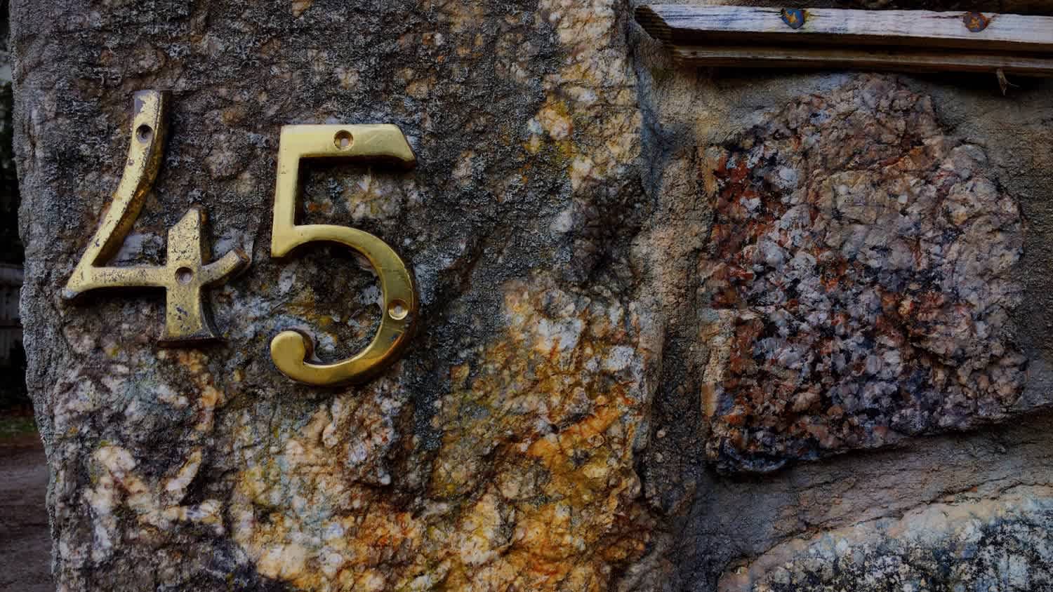 A metallic house number on rock