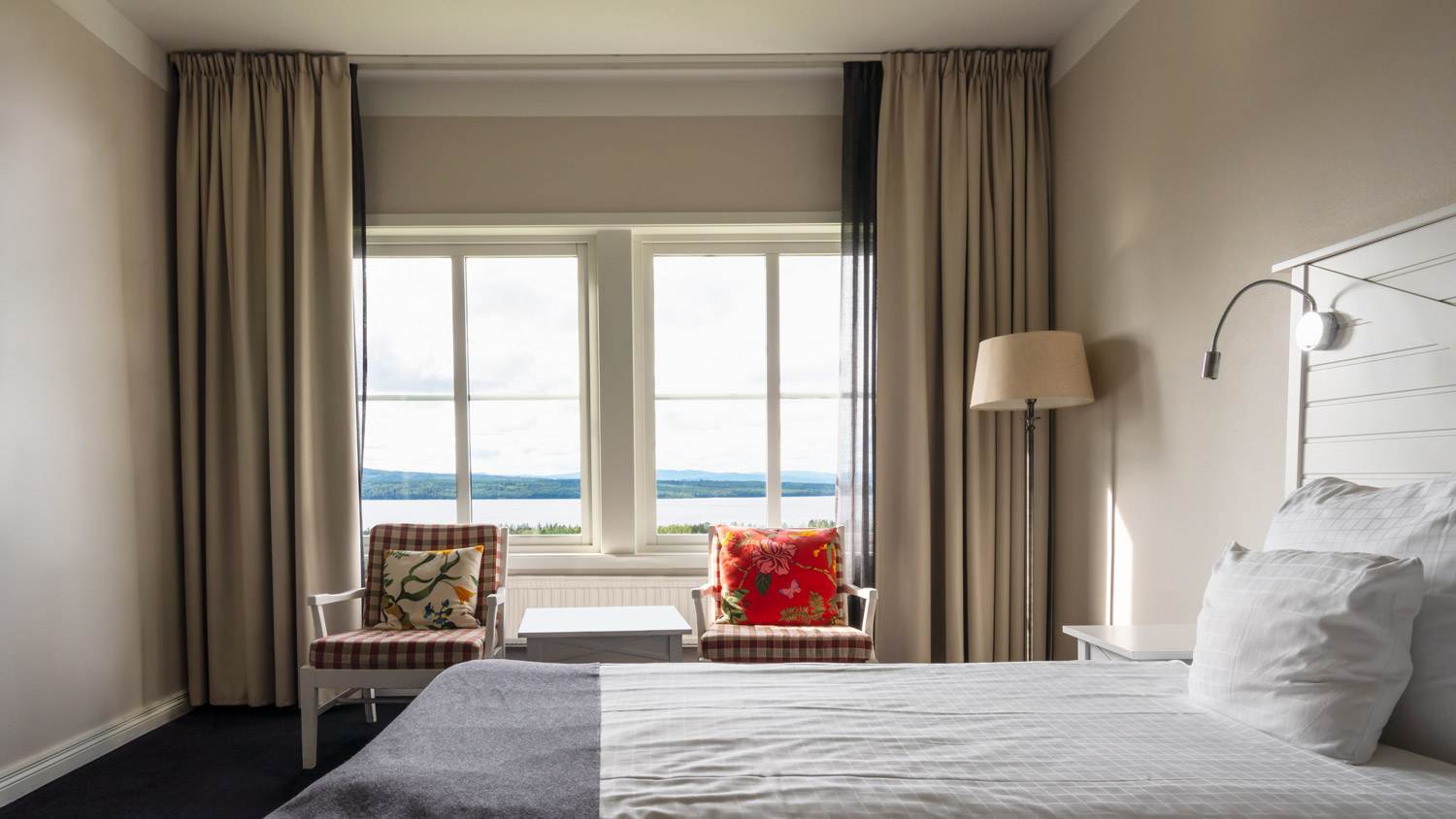 Tidy bedroom with big windows with a landscape view