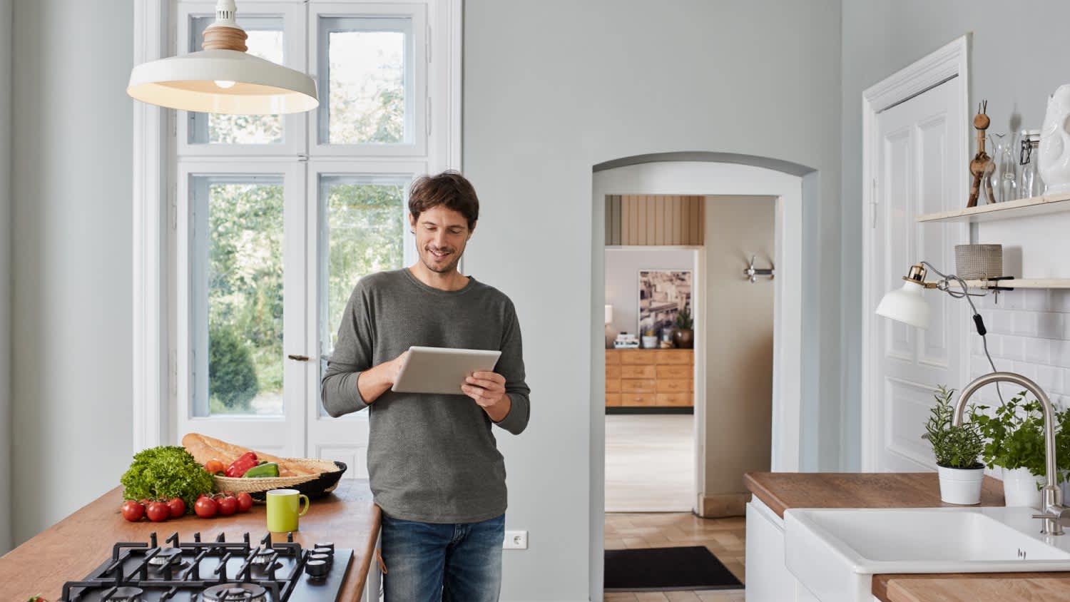 A smiling man using tablet in kitchen