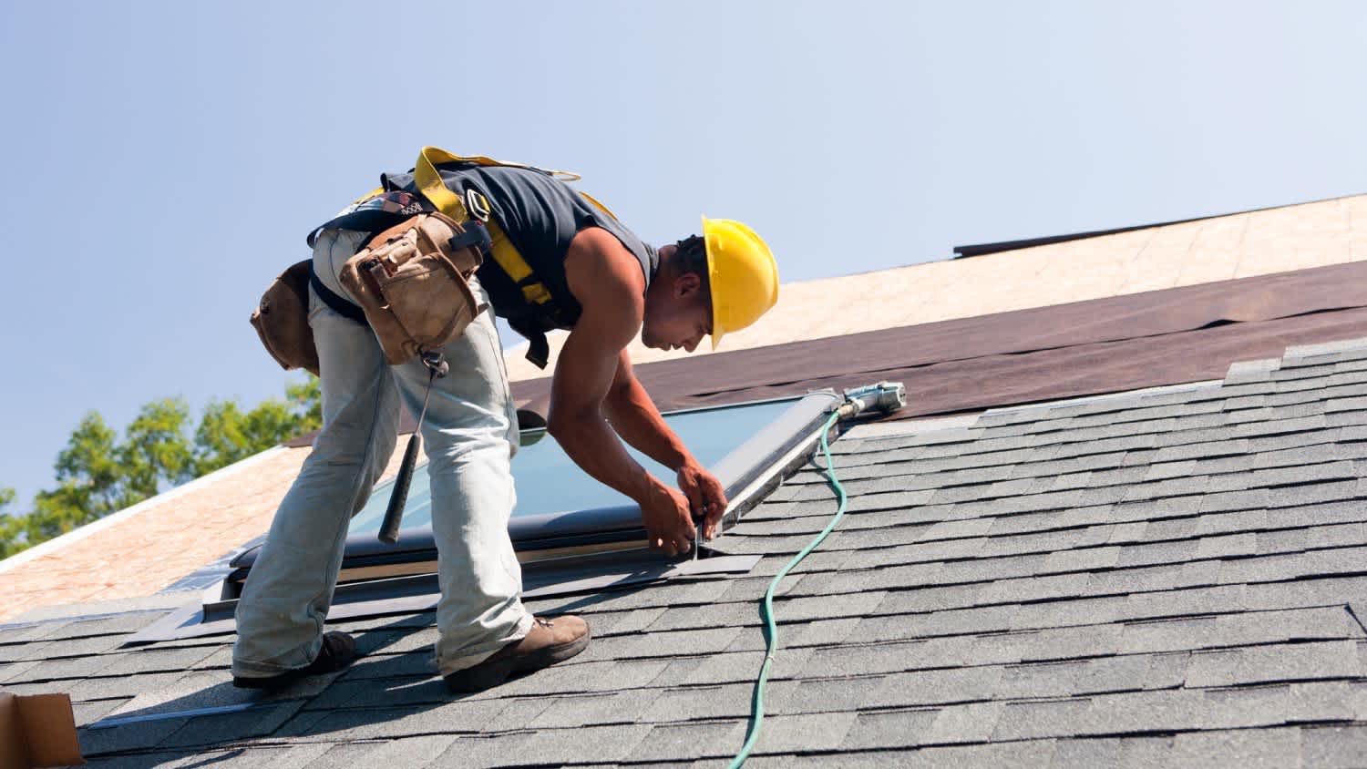 An roofer installing flashing on skylight