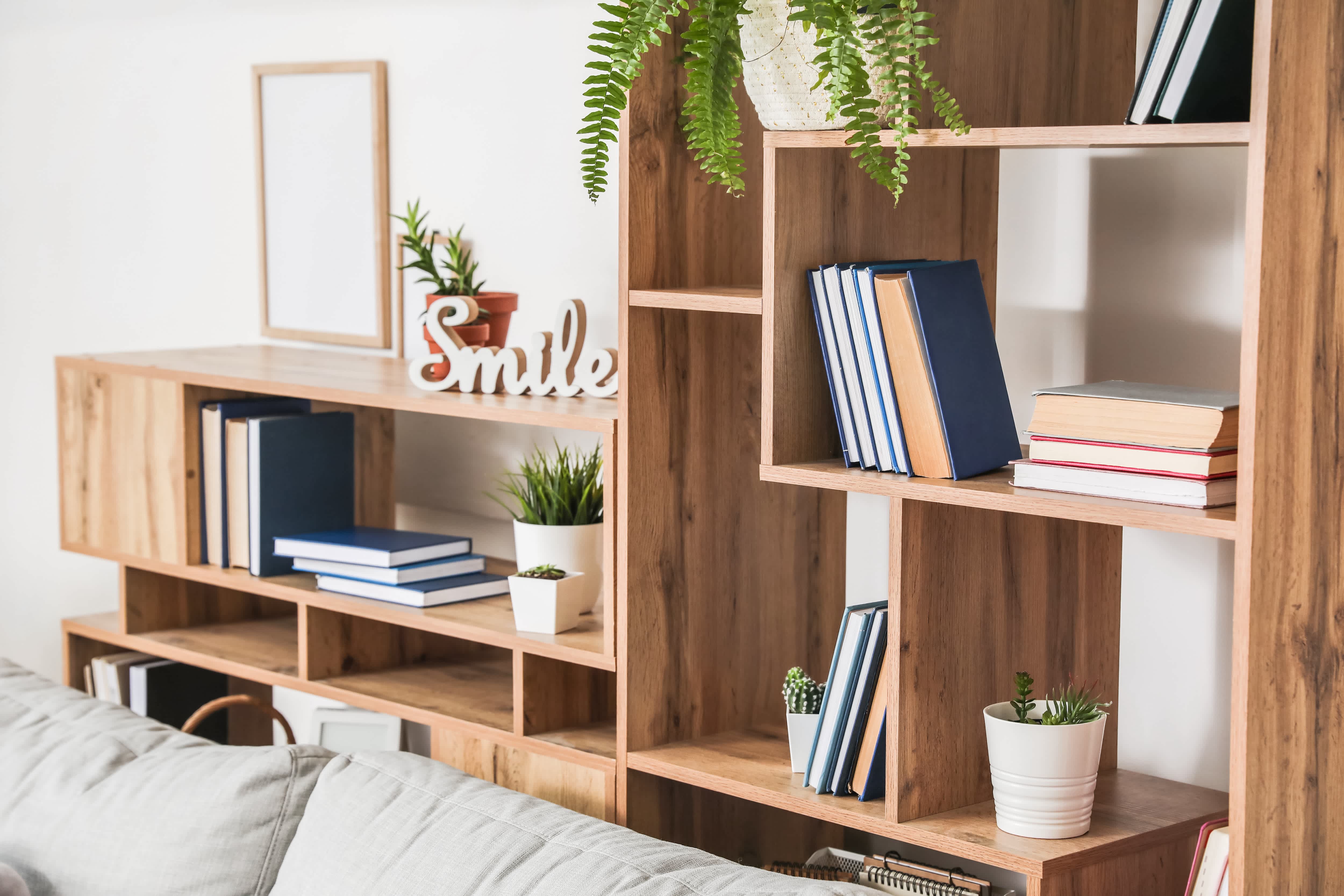 Wooden bookshelf decorated with books, plants, and Smile word art