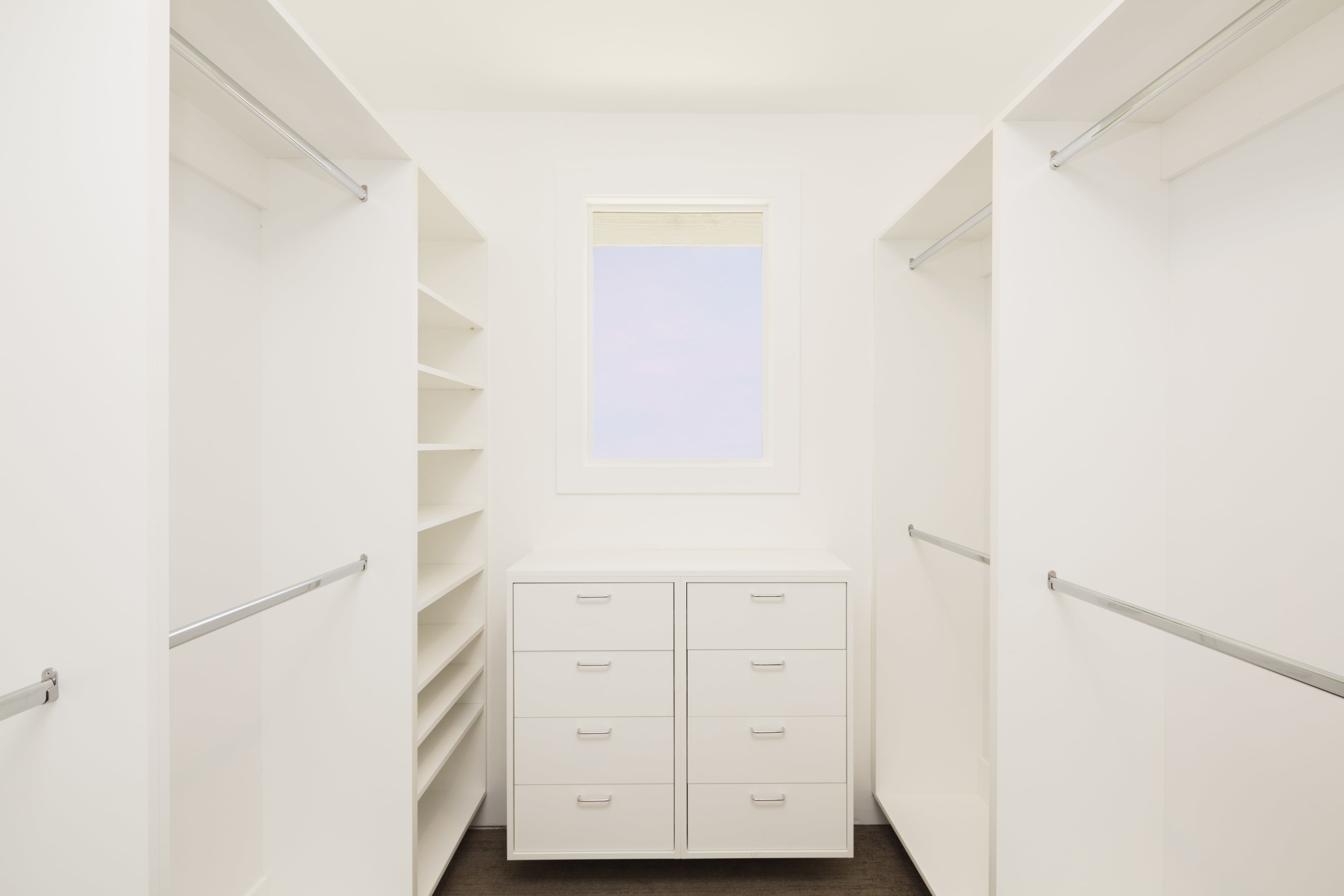 A small dresser in a walk-in closet